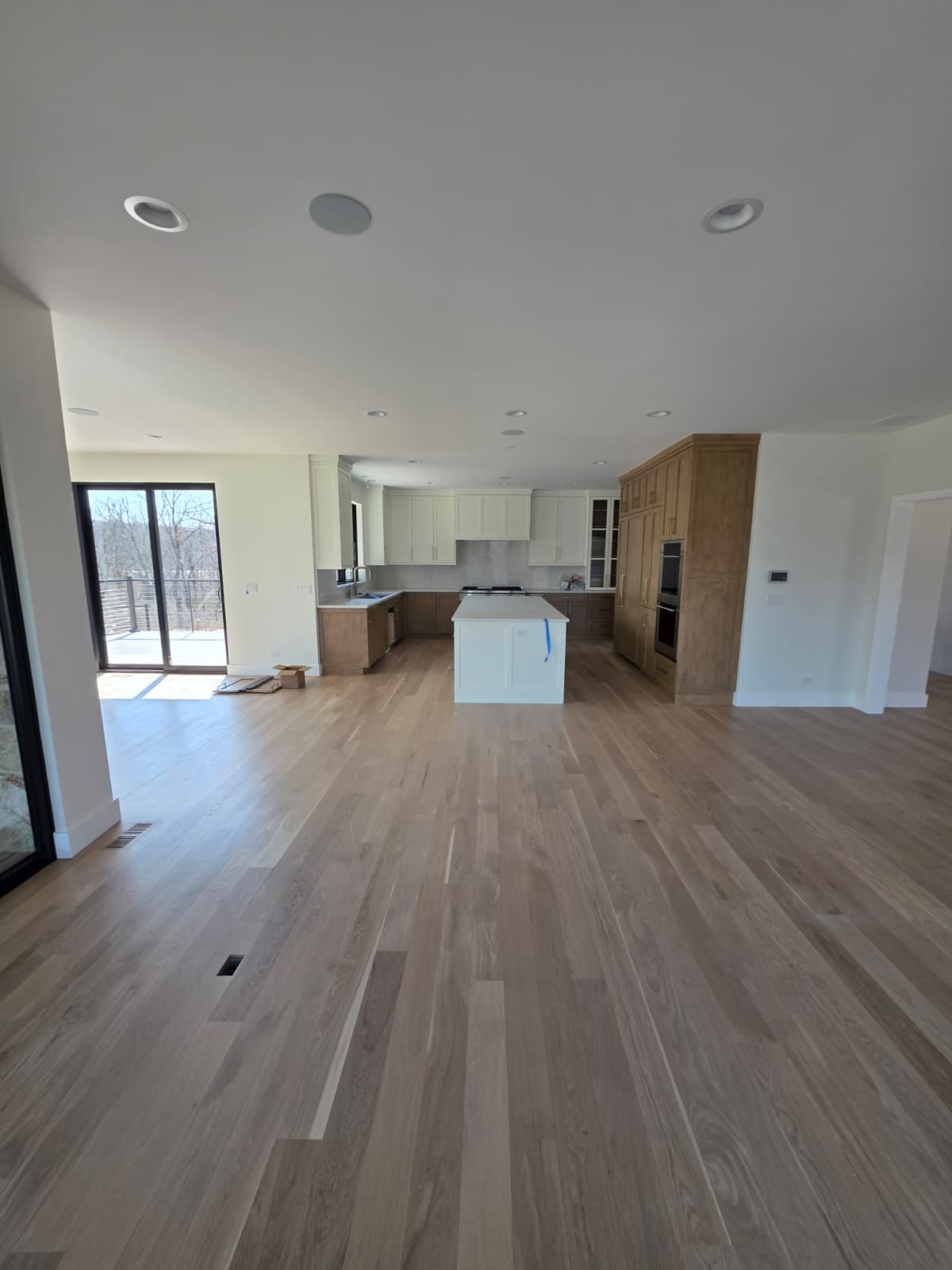 Open-concept living space with wide-plank oak flooring looking toward the kitchen