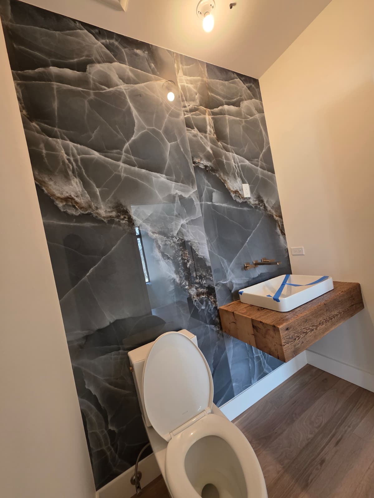 Powder room with a dramatic stone feature wall and a vessel sink on a reclaimed timber shelf