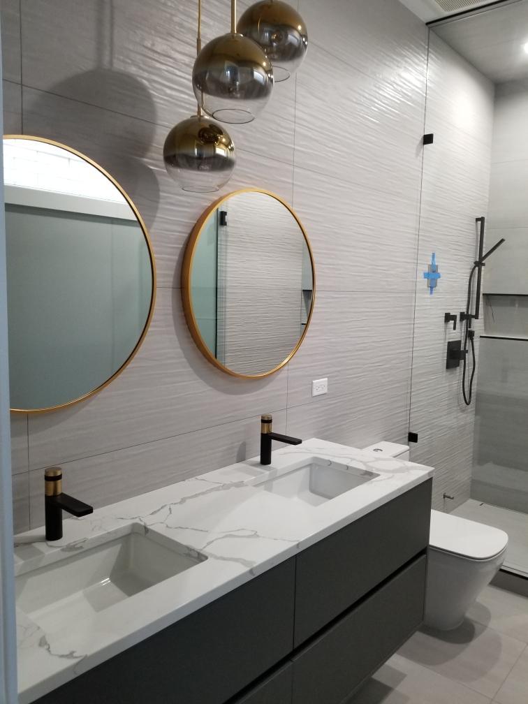 Contemporary bathroom with a floating double vanity, round brass mirrors and glass shower