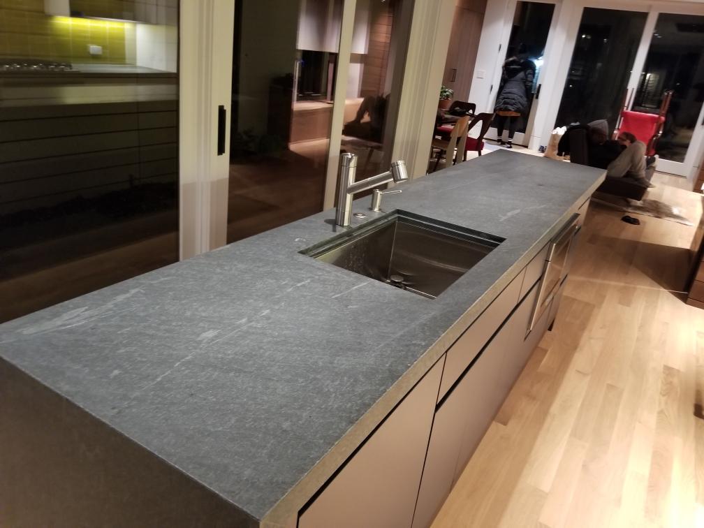 Close view of the dark stone island countertop with an undermount sink