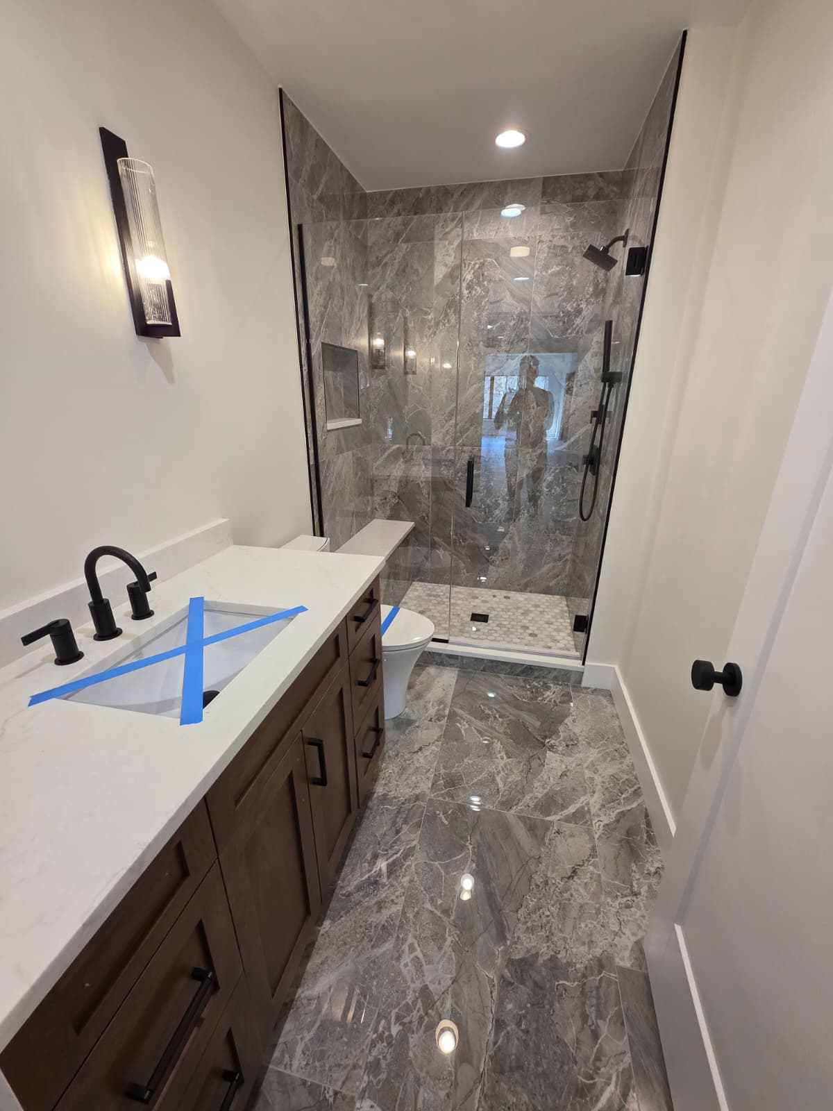 Guest bathroom with a walnut vanity, quartz top, black fixtures and a tiled walk-in shower